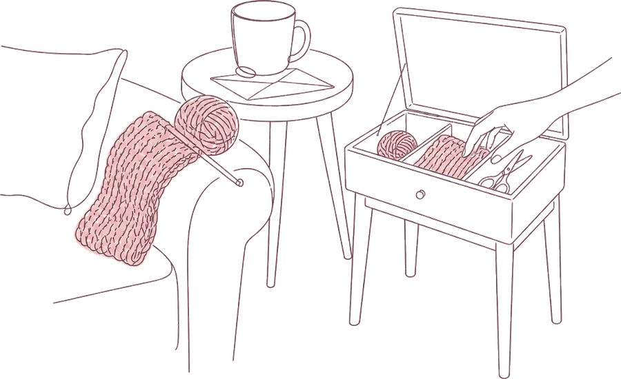 Fine line drawing of the same corner: the knitting on the sofa arm, and beside it a small table with its top open, a hand setting the ball of yarn into its section next to the one pair of scissors